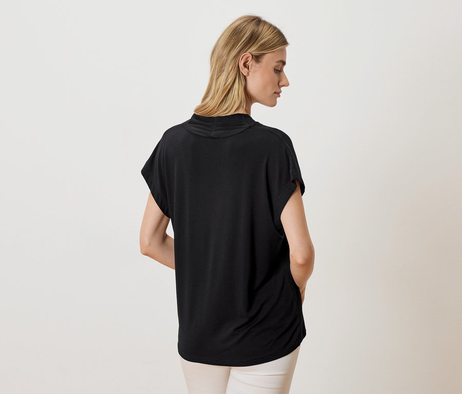 Frau von hinten mit schwarzem Oberteil und heller Hose.