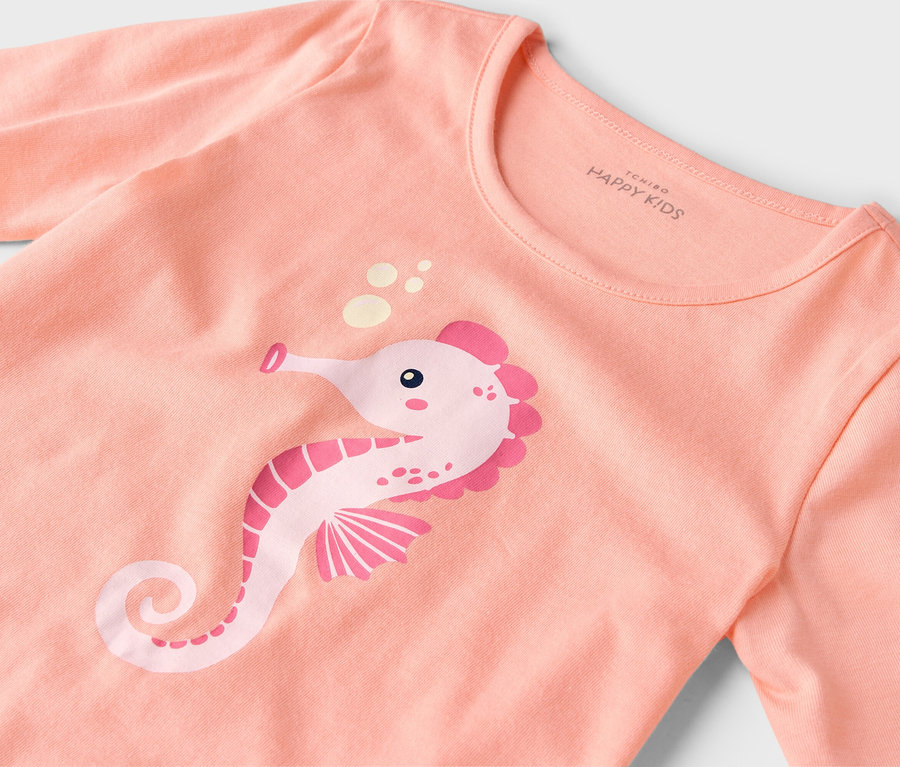 Nahaufnahme eines lachsfarbenen T-Shirts mit einem rosafarbenen Seepferdchen-Aufdruck.