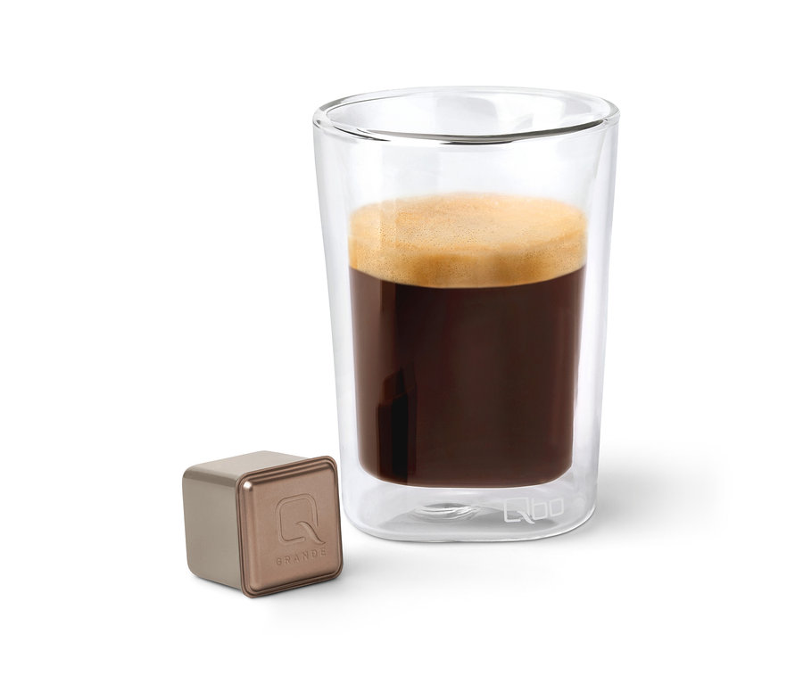 Kaffee in einem Glas neben einer Qbo Caffè Grande BELO SUL Kapsel.