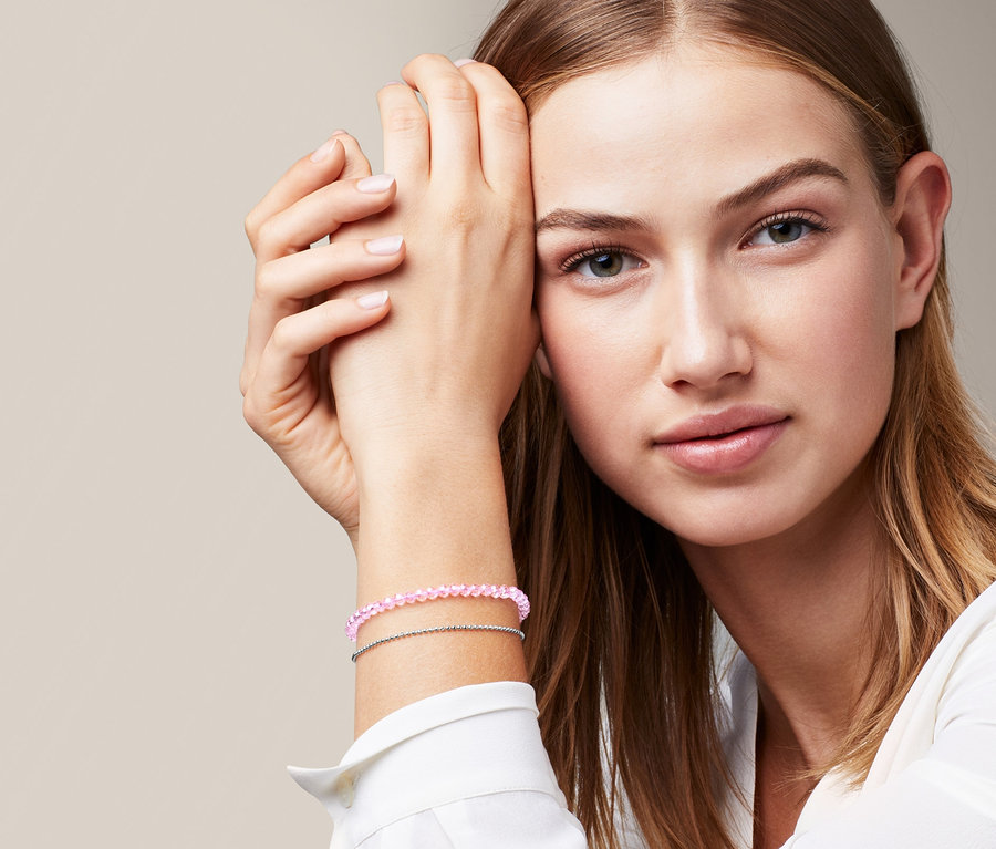 Porträt einer Frau, die ein Armband mit facettierten Glassteinen trägt.