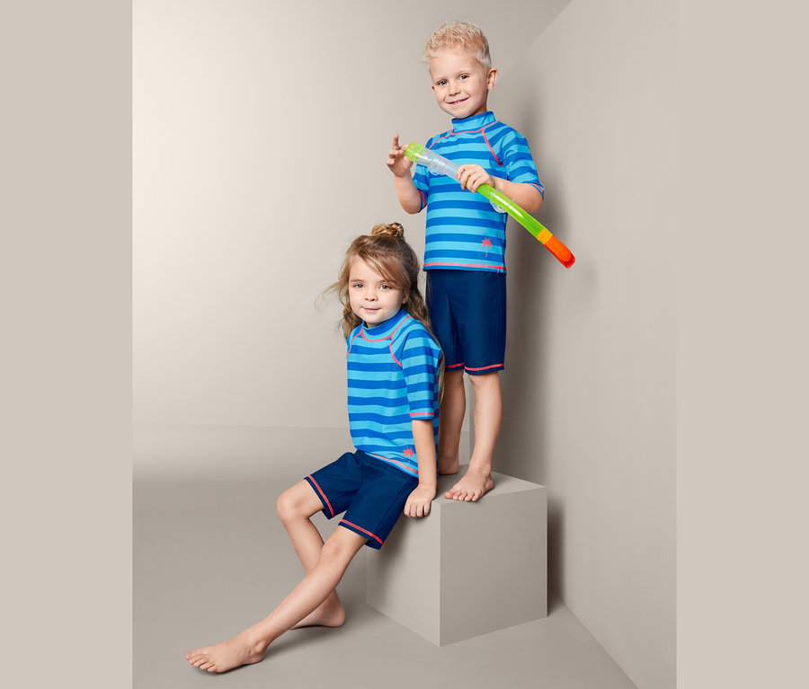 Kinder posieren in UV-Schutz-Kombis. Ein Junge hält einen Schnorchel.