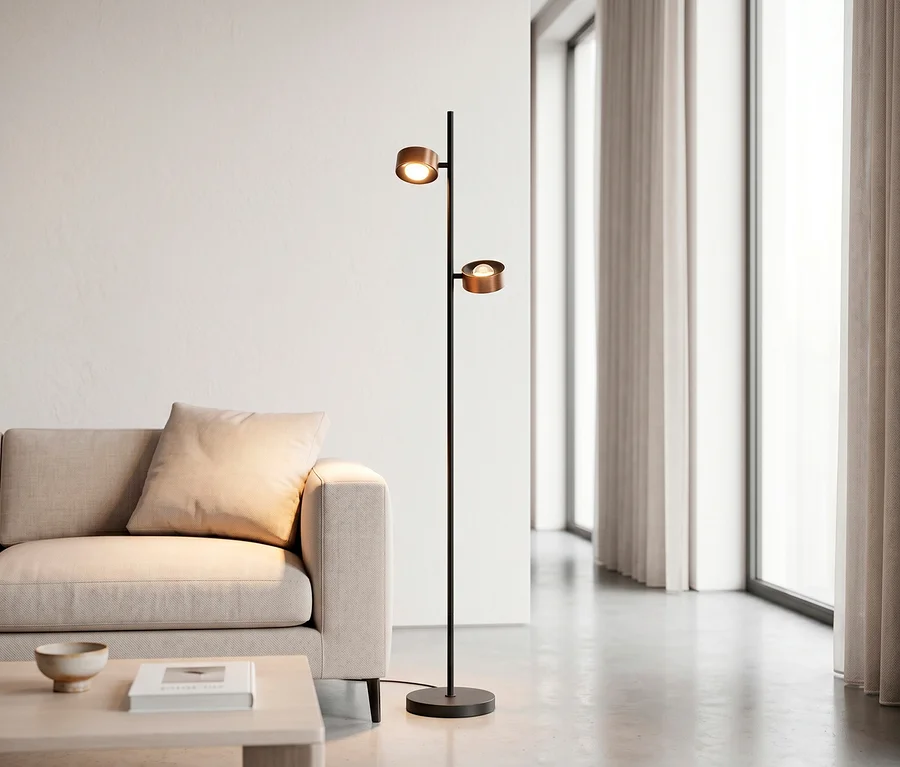 Schwarze Stehlampe mit zwei kupferfarbenen, leuchtenden Köpfen neben einem beigefarbenen Sofa und einem Holztisch in einem modernen Wohnzimmer.