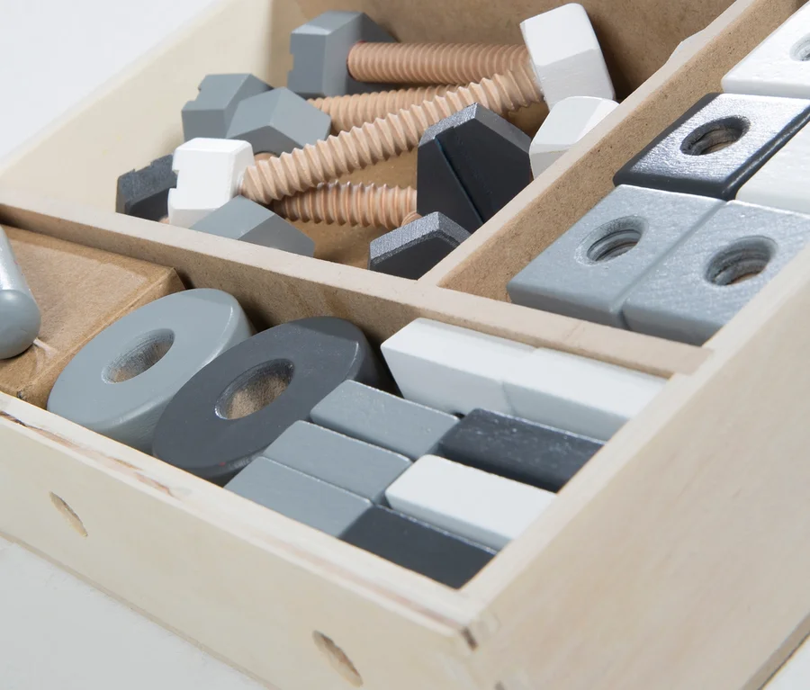 Nahaufnahme eines hellen Holzsortierkastens gefüllt mit dem 48-teiligen roba Holzbaukasten, der Schrauben, Muttern und Blöcke in Grau- und Weißtönen enthält.