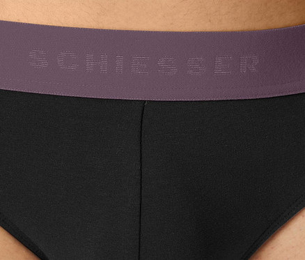 Detailaufnahme eines schwarzen Herrenslips mit lila Bund von Schiesser.