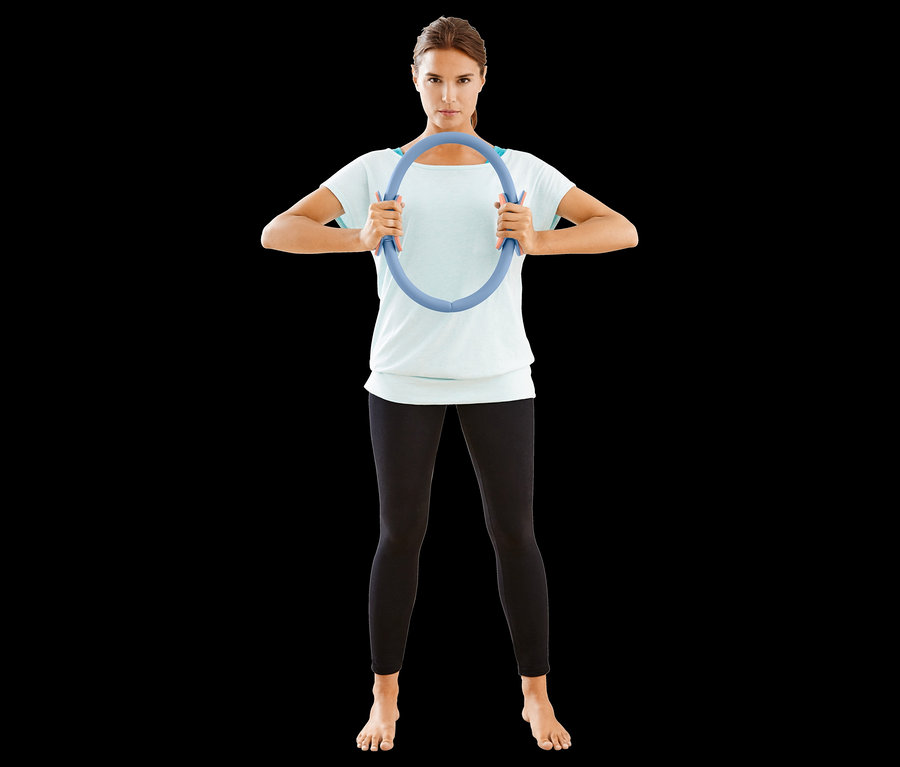 Frau hält Pilatesring.