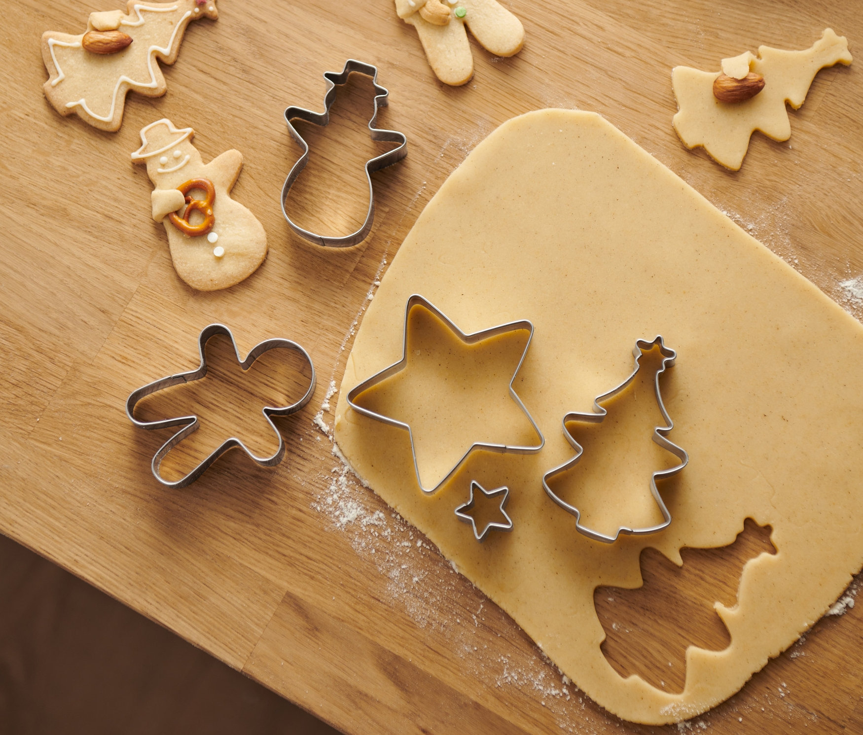 Auf einem Holztisch liegen Kuschelkeks-Ausstecher und gebackene Kekse in verschiedenen Formen.