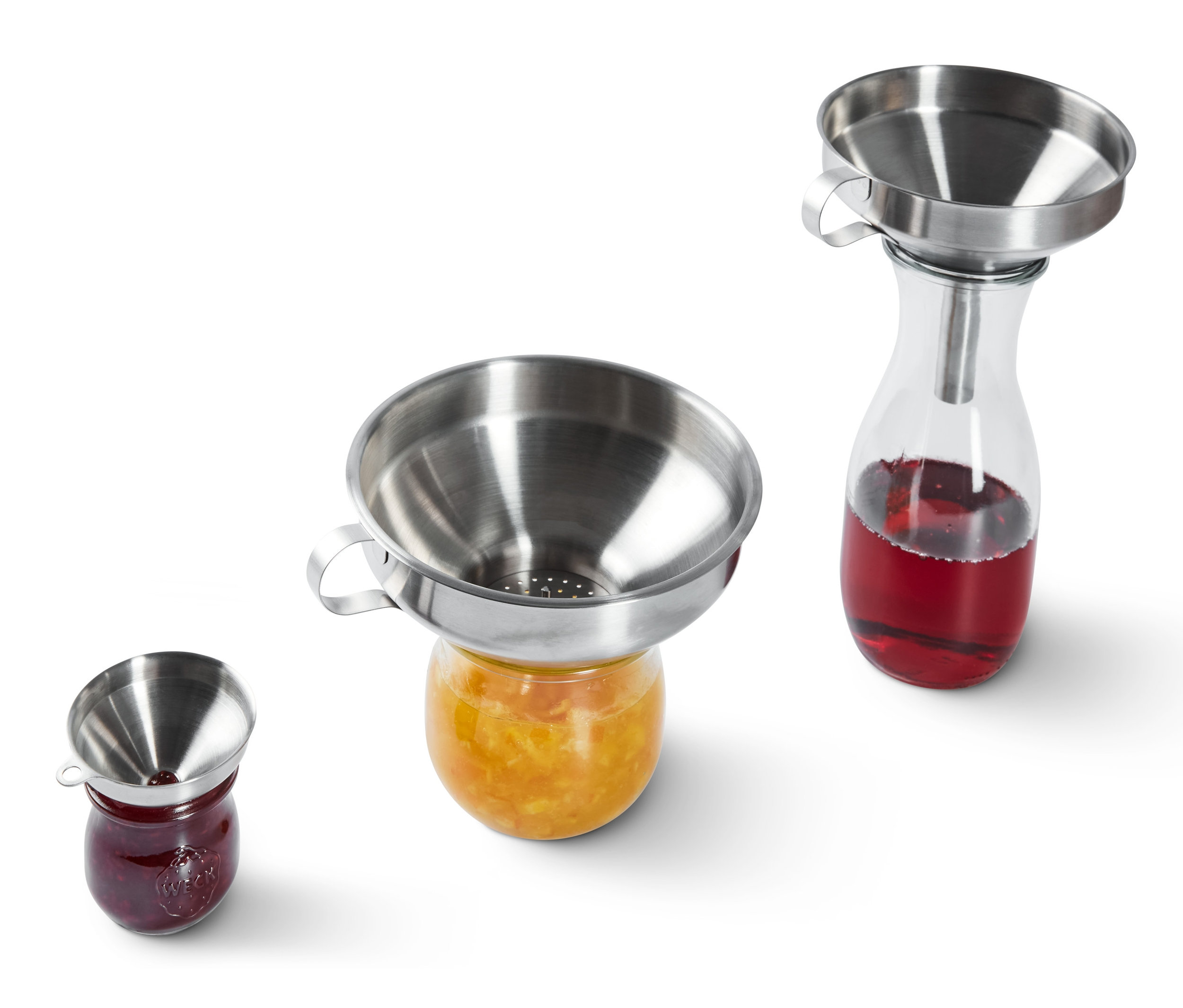 Edelstahltrichter stehen auf Marmeladengläsern.