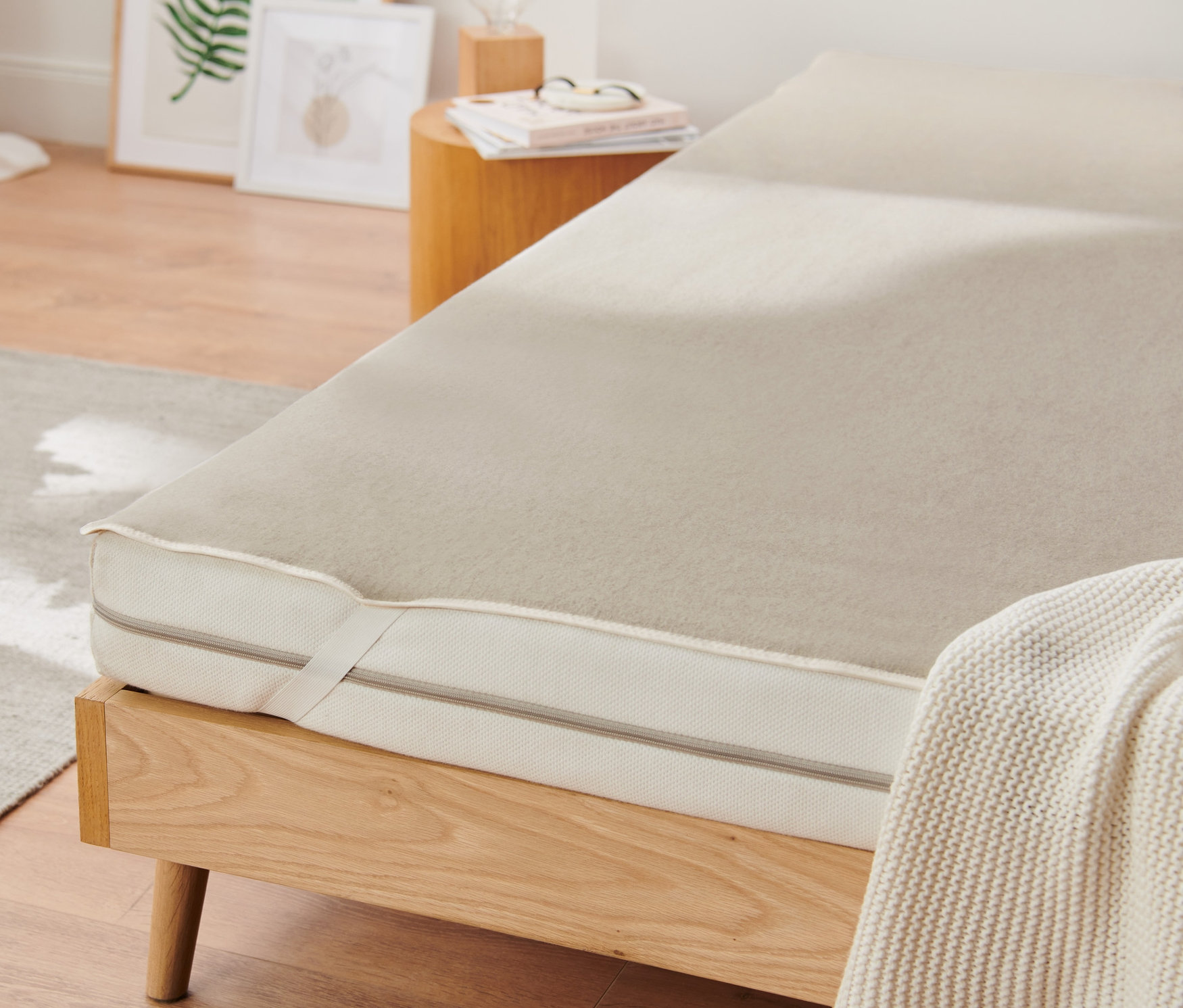 Auf einem Holzbett liegt ein Unterbett mit Leinen.