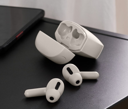 Auf einer schwarzen Tischplatte liegen TWS-In-Ear-Kopfhörer, ein Telefon und eine Vase mit Blumen.