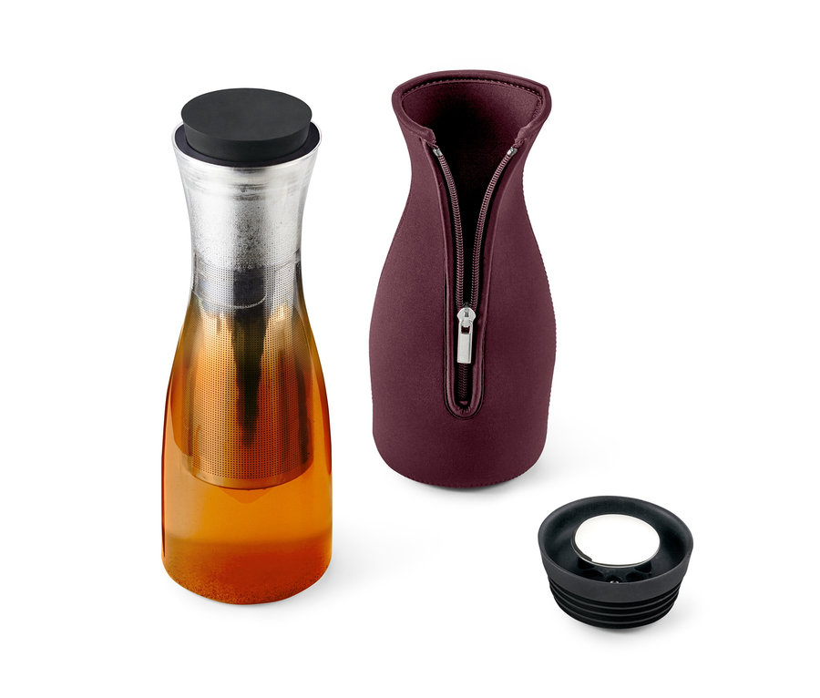 Eine Glas-Teekanne mit Tee, daneben eine Kannenabdeckung und ein Deckel.