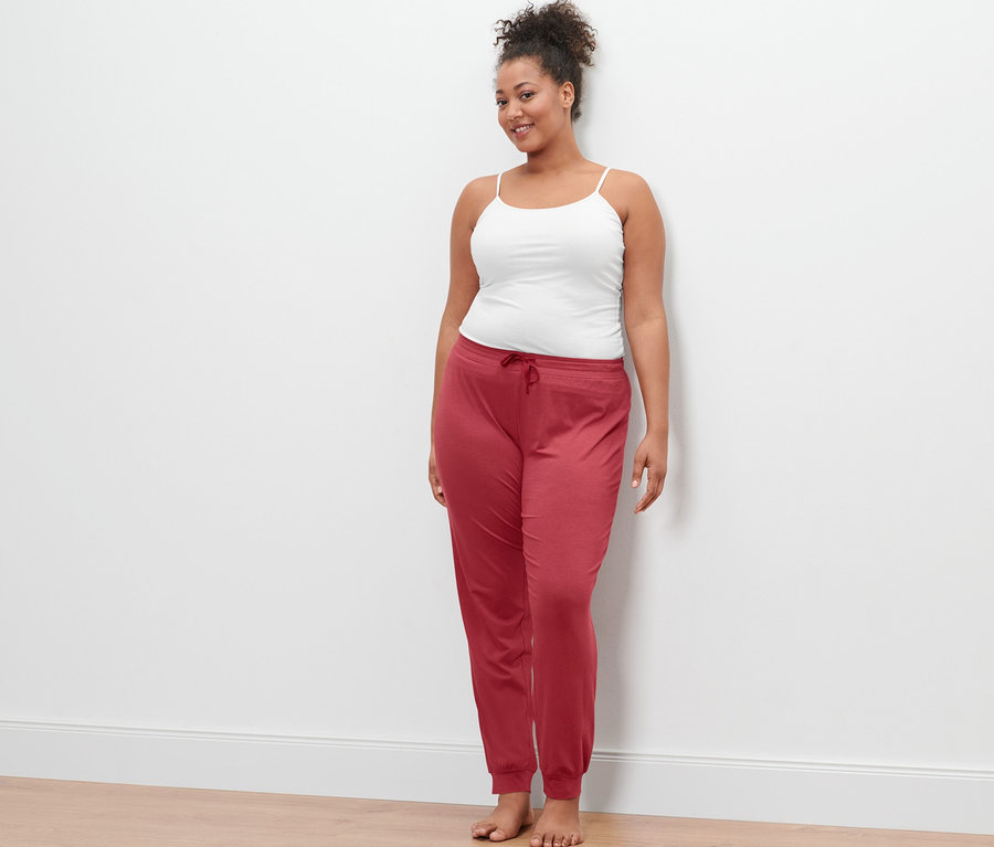 Eine Frau trägt ein weißes Hemdchen und eine Pyjamahose.