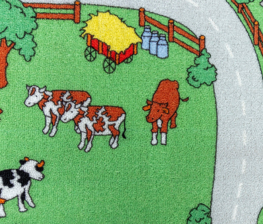 Grüner Spielteppich mit Cartoon-Kühen, Straße, Bäumen und Zäunen. Spielteppich BAUERNHOF, ca. 140 x 200 cm und ca. 95 x 200 cm sind sichtbar.