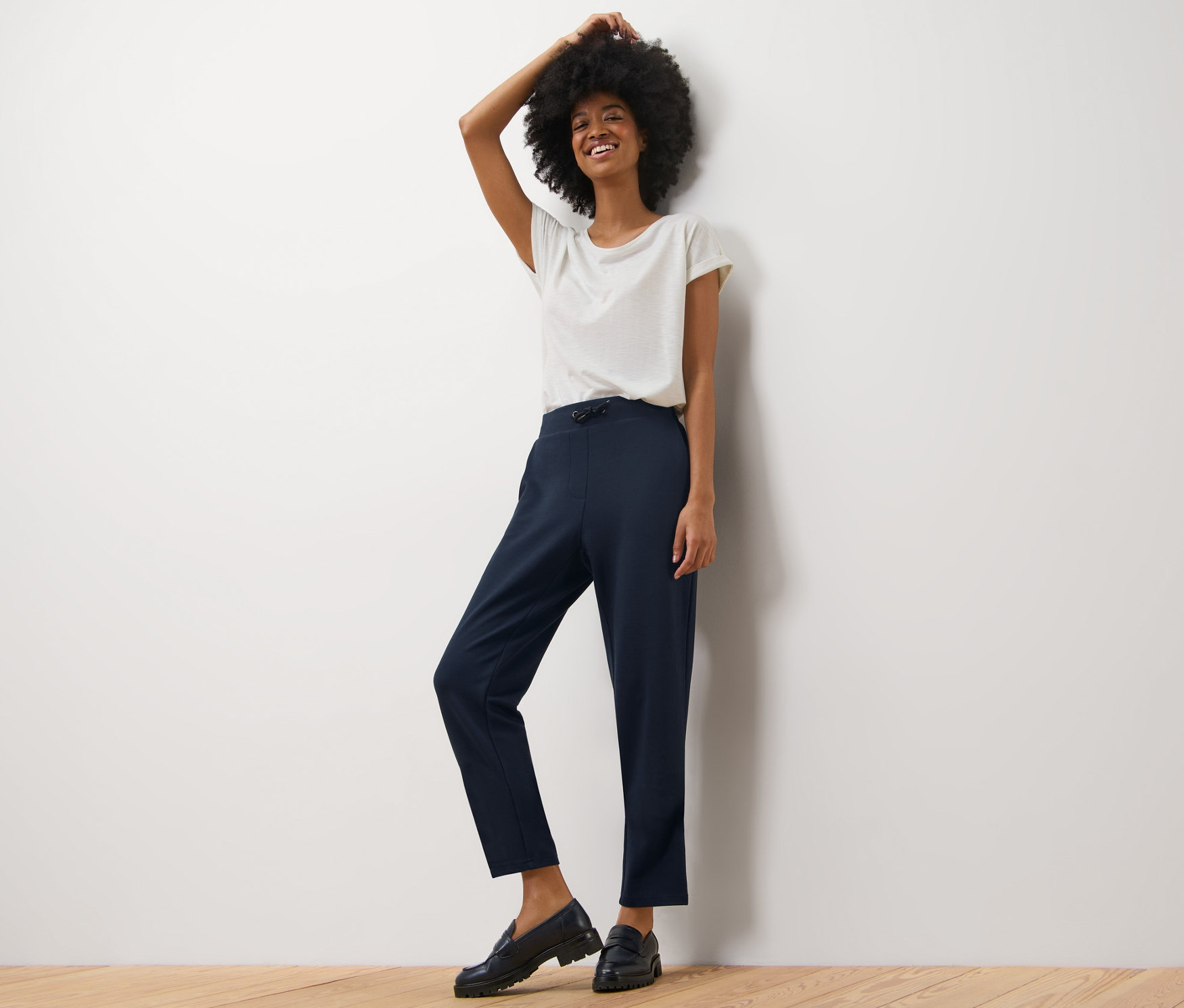 Frau posiert in Joggpants und weißem T-Shirt.