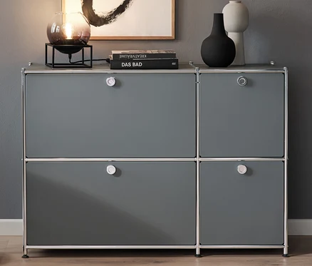 Im Wohnzimmer stehen eine Bogenleuchte mit Rauchglas-Schirmen neben einem grauen Sideboard »CN3« mit 4 Klappen. Über dem Sideboard hängt eine Pendelleuchte mit Rauchglas-Schirm und darauf steht eine Tischleuchte mit Rauchglas-Schirm.