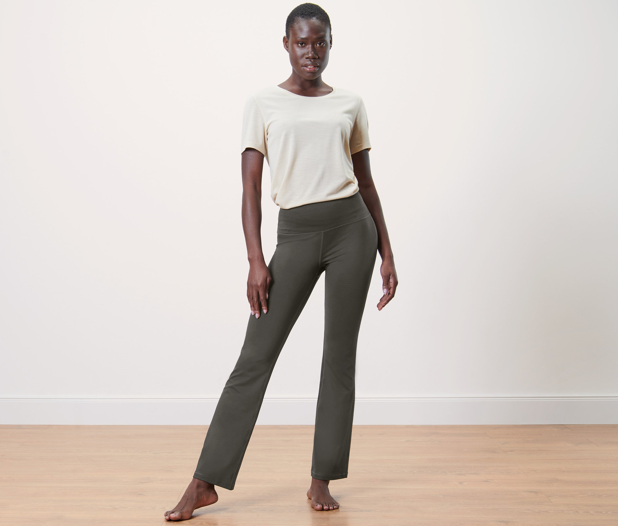 Frau posiert im Studio und trägt eine olivfarbene Bodyforming-Sporthose.