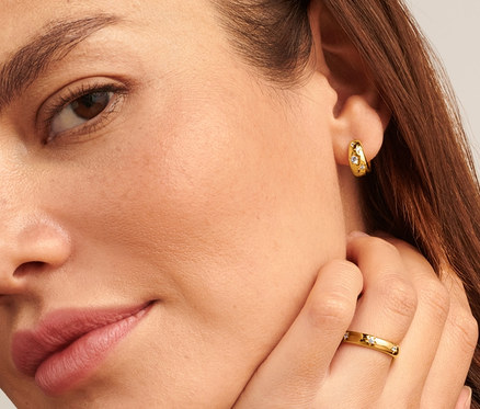 Frau mit 925 Silber Ring Stars am Finger und 925 Silber Creolen Stars in den Ohren.