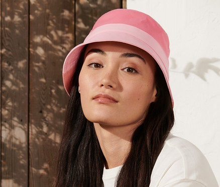 Frau sitzt auf einer Bank und trägt einen Trekking-Hut.