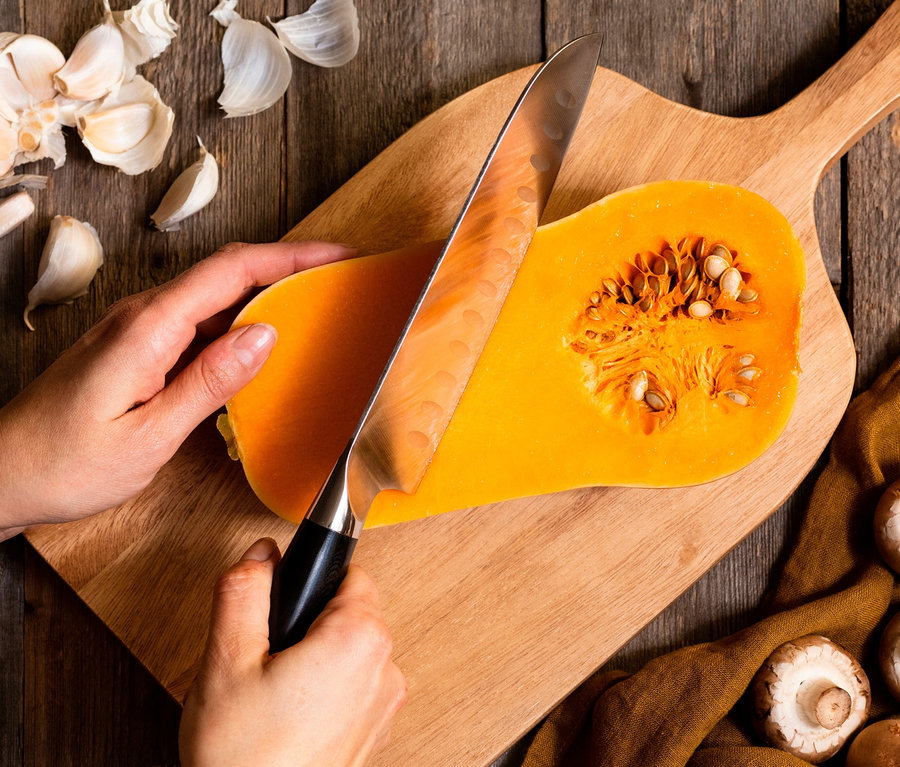 Frau schneidet Kürbis mit WILFA Santoku-Messer EGO Sandvik ES18SK auf Holzbrett.