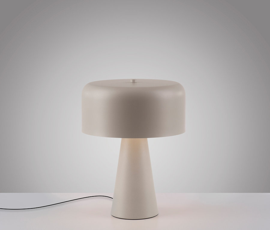 Beige Tischlampe mit rundem Schirm auf einem weißen Tisch.