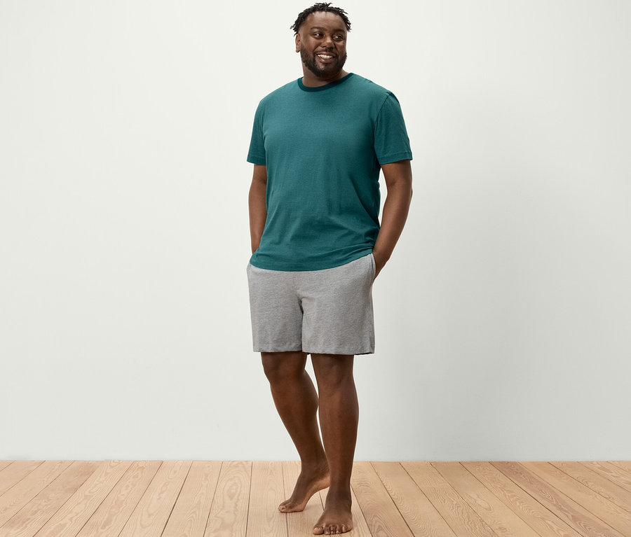 Mann steht mit Händen in den Taschen der Shorty-Pyjama-Set-Shorts.