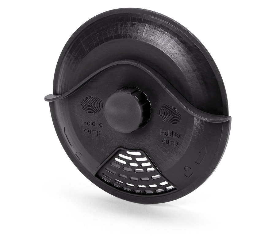 Detailansicht einer schwarzen Plastikabdeckung mit der Aufschrift "Hold to dump" und einem Gitter.