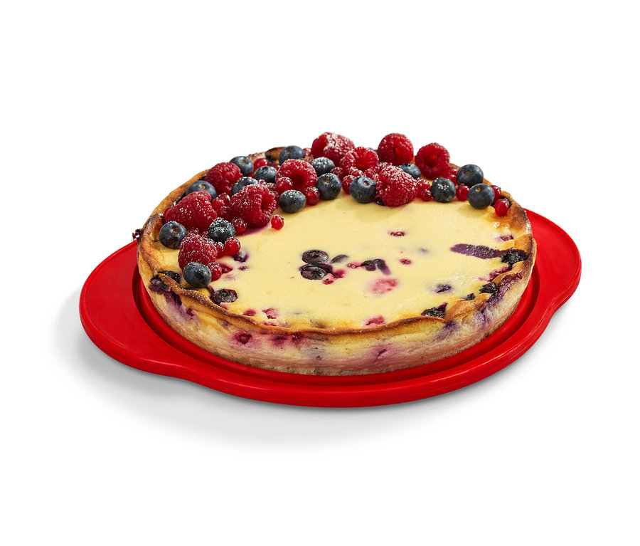 Ein mit Früchten dekorierter Kuchen auf einer roten faltbaren Kuchenform.