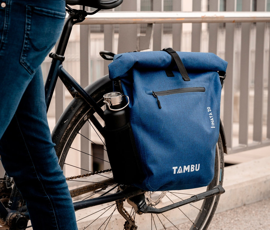 Mann steht neben Fahrrad mit blauer Tambu Fahrradtasche INAYA und Wasserflasche.