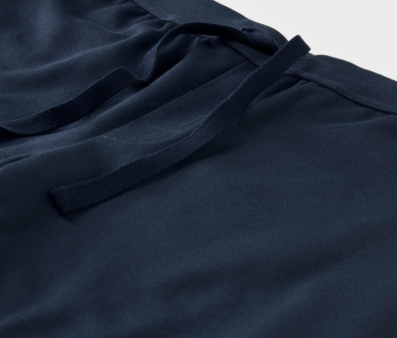 Detailaufnahme einer blauen Stoffhose mit Kordelzug in der Taille.