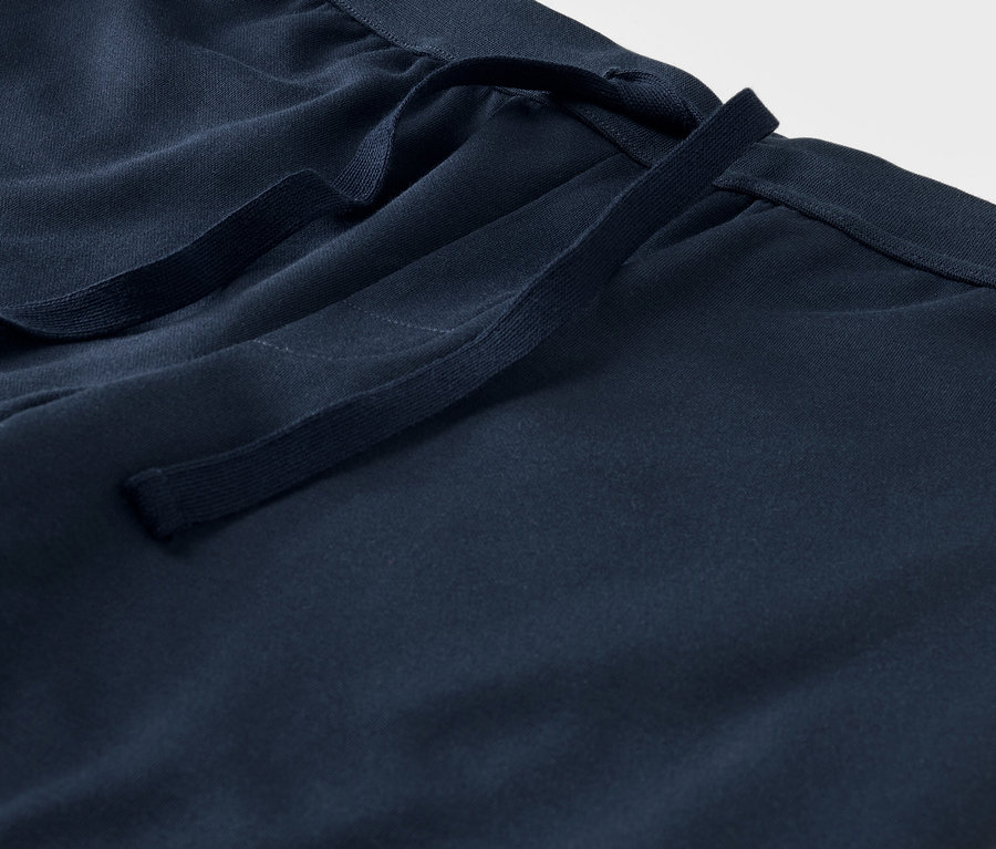 Detailaufnahme einer blauen Stoffhose mit Kordelzug in der Taille.