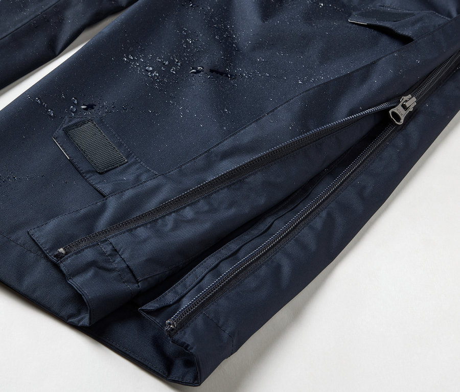 Detailaufnahme einer marineblauen High-Tech-Regenhose mit durchgehendem Reißverschluss.