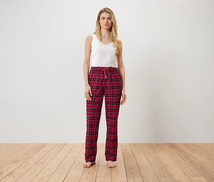 Frau steht und trägt ein weißes Top und eine rot karierte Hose.