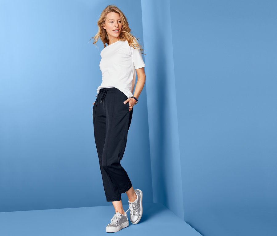 Blonde Frau posiert in weißem T-Shirt und Webhose.