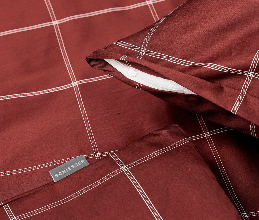 Nahaufnahme von SCHIESSER Bettwäsche mit Karomuster in Burgunderrot mit weißen Linien.