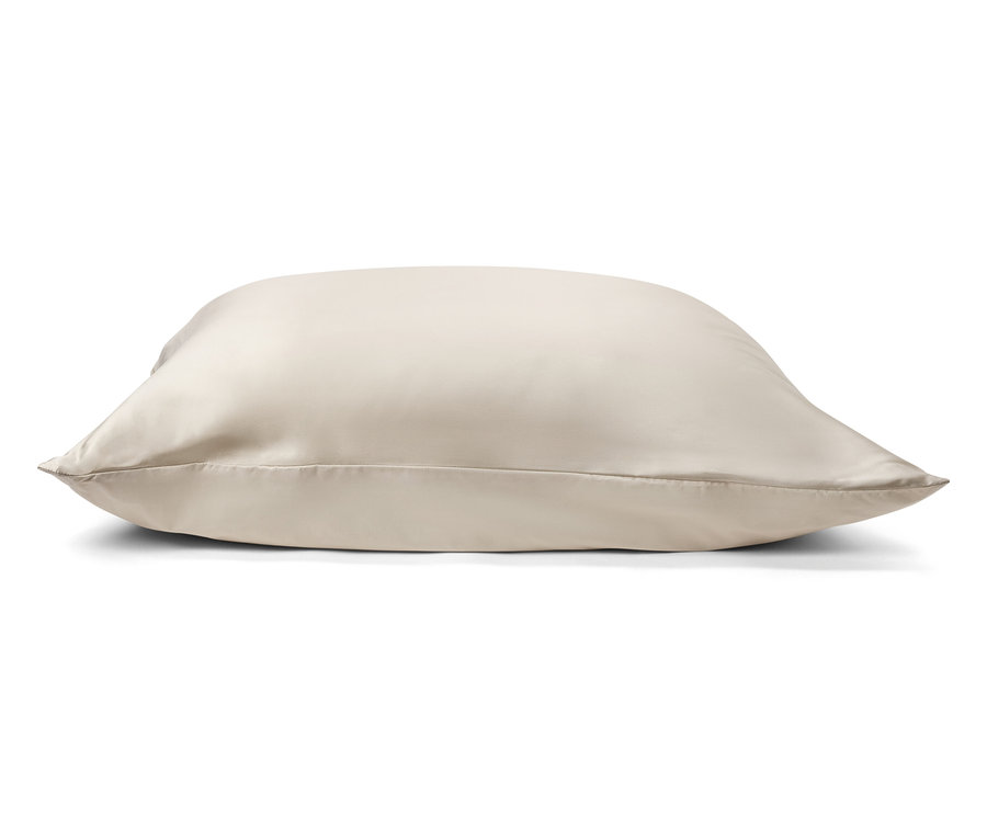 Ein beiges Satinkissen liegt auf einem weißen Hintergrund.