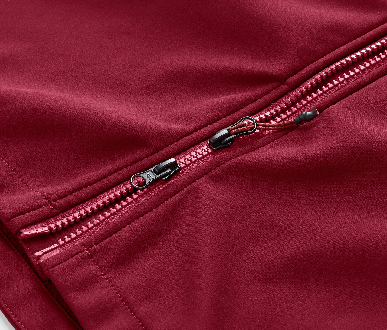 Detailansicht des Reißverschlusses eines dunkelroten Softshellmantels.