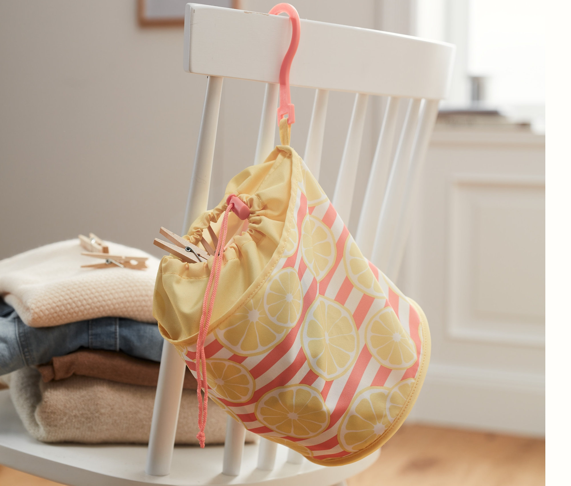 Klammerbeutel hängt an einem Stuhl neben einem Stapel Kleidung.