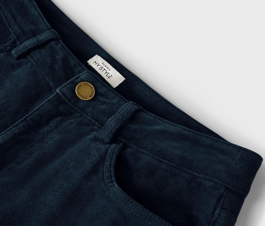 Detailaufnahme einer dunkelblauen Hose mit Knopf und Tasche.