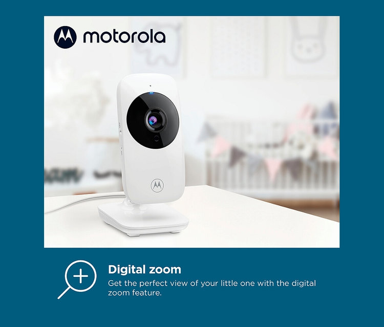 Ein weißes Motorola »VM482« Video-Babyphone steht auf einem weißen Tisch, im Hintergrund ein Kinderbett.