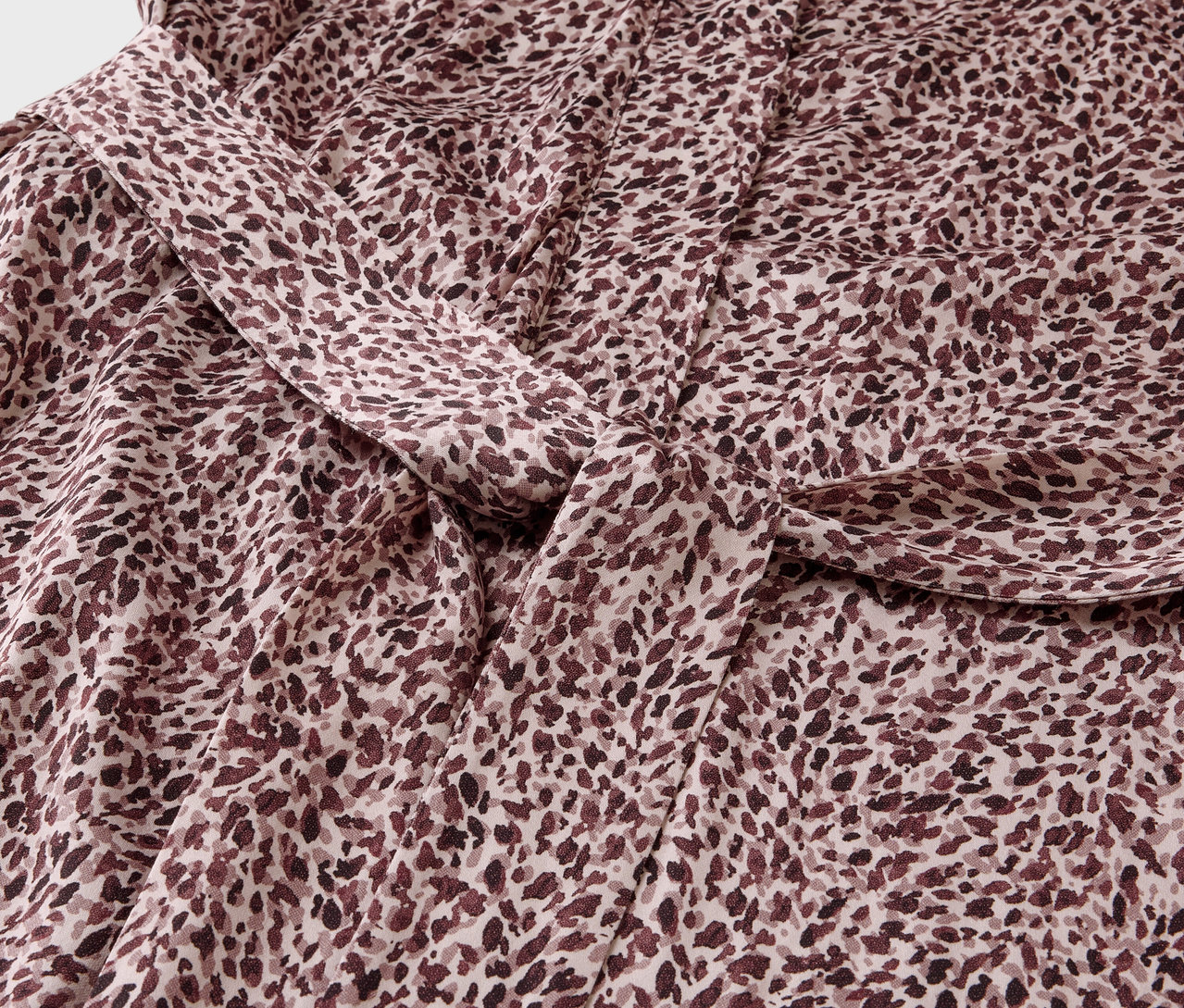 Detailaufnahme eines Stoffes mit braunem Fleckenmuster und einem Knoten.