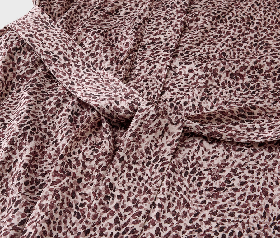Detailaufnahme eines Stoffes mit braunem Fleckenmuster und einem Knoten.
