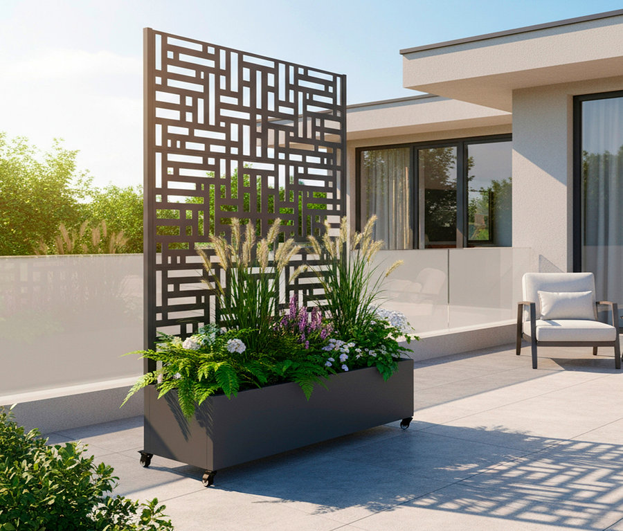 Draußen steht ein grauer Pflanzkasten mit Rädern und einem vertikalen, geometrisch gemusterten Sichtschutz, bepflanzt mit verschiedenen Pflanzen.