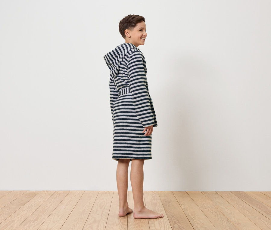 Ein Junge steht barfuß in einem gestreiften Bademantel.