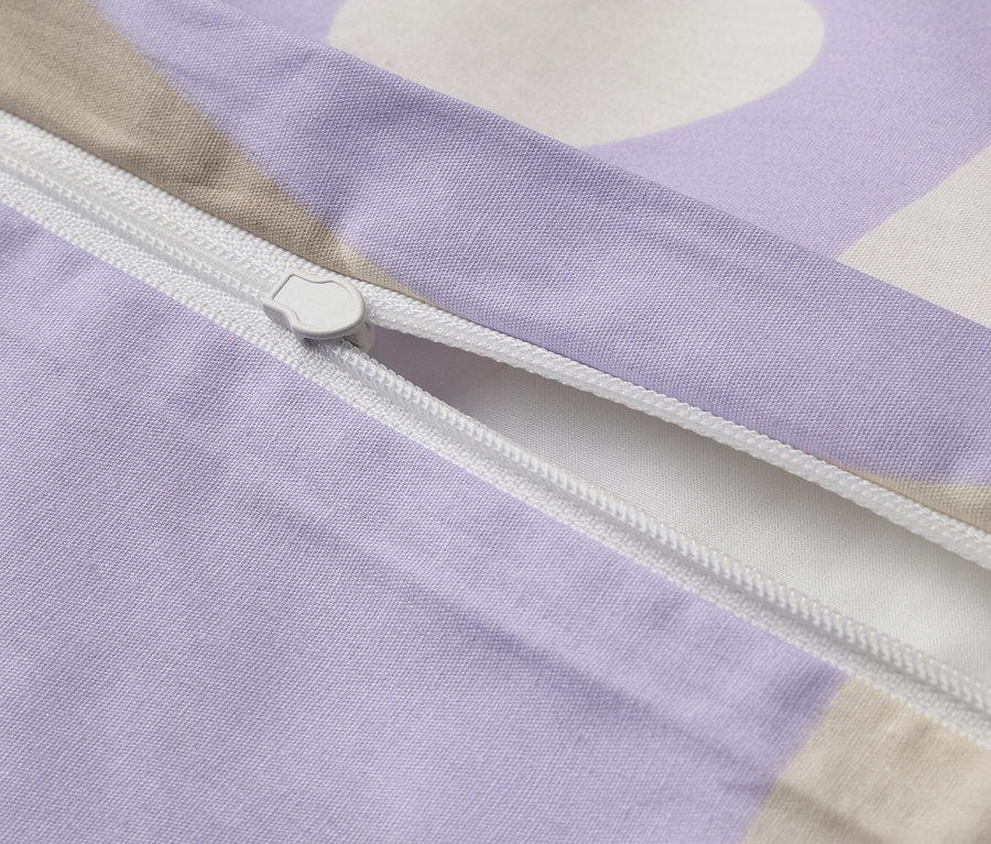 Nahaufnahme eines teilweise geöffneten, lila gemusterten Bettbezugs mit einem weißen Reißverschluss.