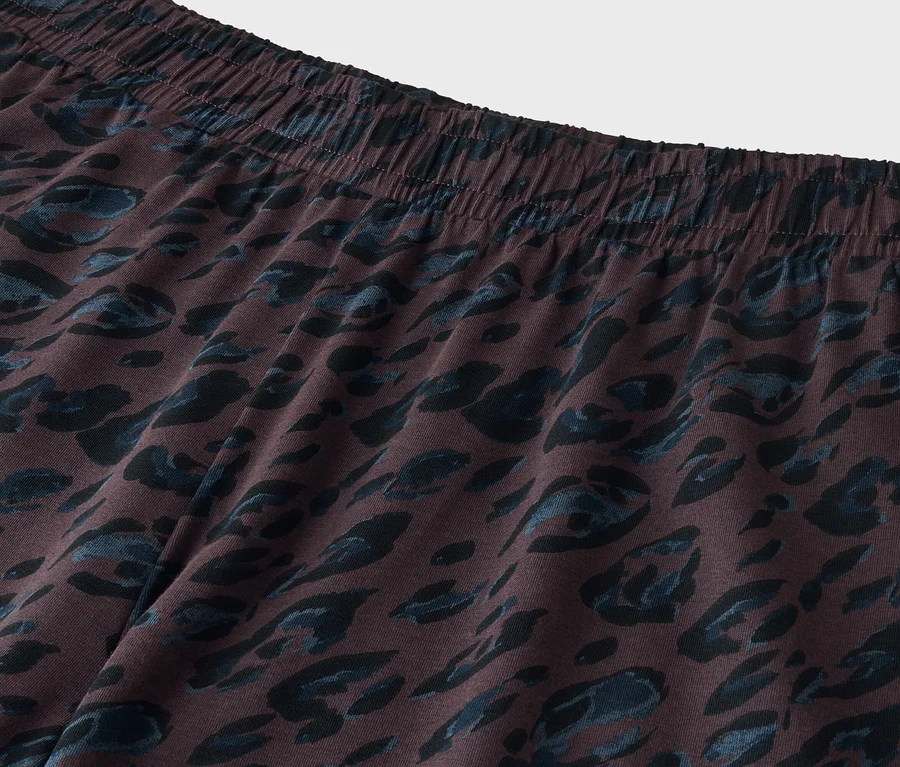 Nahaufnahme eines dunkelbraunen Stoffes mit elastischem Bund und dunkelblauem, abstraktem Animal-Print.