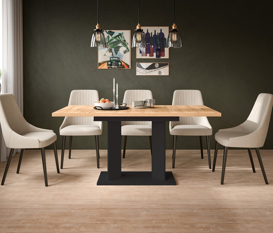 Ein modernes Esszimmer mit einem hellen Holztisch auf dunklem Sockel, umgeben von sechs beigefarbenen Polsterstühlen. Auf dem Tisch stehen eine Obstschale und Kerzen. Drei Glaspendelleuchten und drei gerahmte Kunstwerke zieren die dunkelgrüne Wand.