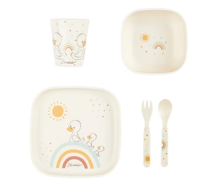 Cremefarbenes Kindergeschirrset. Der Becher zeigt zwei Entenküken und einen Regenbogen. Die Schale hat eine Sonne und einen Regenbogen. Der Teller zeigt eine Entenfamilie auf einem Regenbogen mit Sonne. Gabel und Löffel sind mit Sonne bzw. Regenbogen verziert, alle Teile mit bunten Punkten.