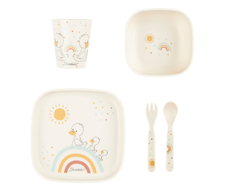 Cremefarbenes Kindergeschirrset. Der Becher zeigt zwei Entenküken und einen Regenbogen. Die Schale hat eine Sonne und einen Regenbogen. Der Teller zeigt eine Entenfamilie auf einem Regenbogen mit Sonne. Gabel und Löffel sind mit Sonne bzw. Regenbogen verziert, alle Teile mit bunten Punkten.