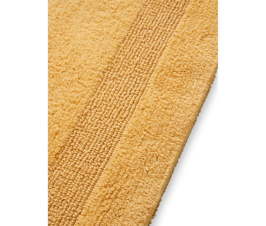 Gelbe Badematte mit flauschiger Textur und einem gerippten Streifenmuster.