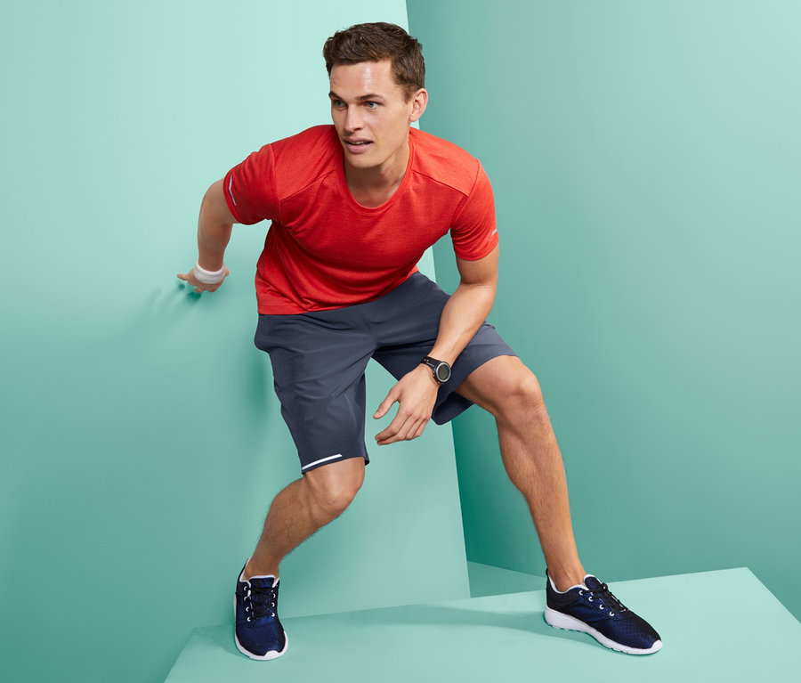 Mann in Sportshorts steht an einer Wand.