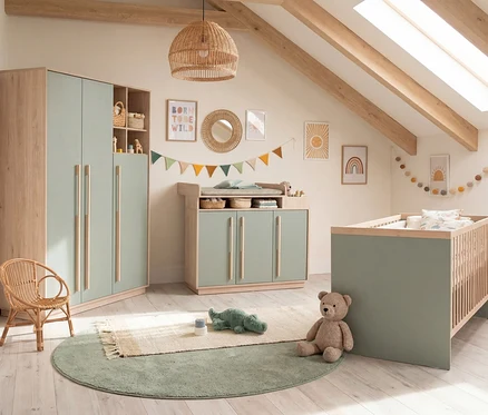 Ein Kinderzimmer mit dem Roba 3-teiligen Kinderzimmer-Set "Selva" in Reed Green und Virginia Chestnut, bestehend aus Kleiderschrank, Wickelkommode und Babybett. Ein Rattanstuhl, grüne Teppiche und bunte Dekorationen schmücken den Raum.